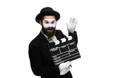 Joyful man in the image mime, dressed in black and white suit with movie board, isolated on a white backgroundの写真素材