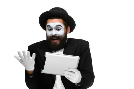 Man with a face mime working on a laptop isolated on a white background. concept of thinking in businessの写真素材