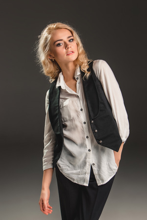 Beauty blond woman  in a black suit and white shirt on a gray backgroundの写真素材