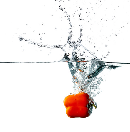 Fresh red pepper drops into a water, isolated on white backgroundの写真素材