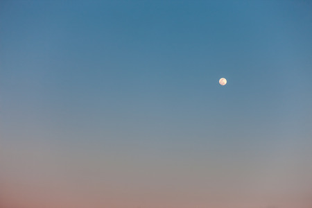 The Full Moon in daylight blue skyの写真素材