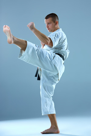 Man in white and black belt training karate over blue background.の写真素材