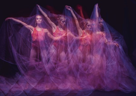 a sensual and emotional dance of beautiful ballerina through the veil on a dark backgroundの写真素材