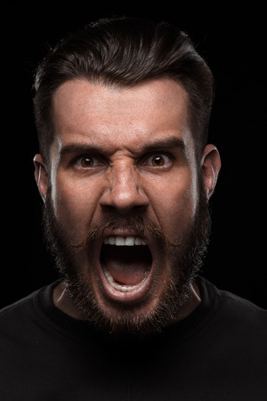 Portrait of young frightened  crying man with a beard and mustache in studio on black backgroundの写真素材