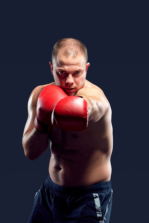 Young boxer in red gloves boxing over black backgroundの写真素材