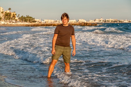 The young guy standing in the waves on Croissette Beach in Cannesの写真素材