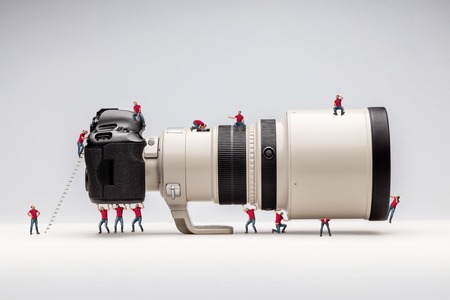 Miniature man woking with camera. Macro photo. the concept of work of a professional photographerの写真素材
