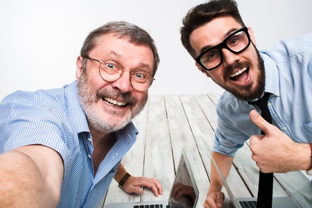 Two smiling colleagues taking the picture to them self sitting in the office, happy friends with...