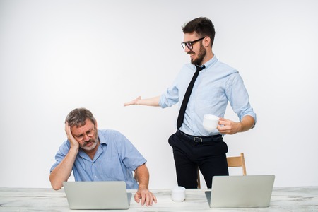 The two colleagues working together at office on white  background. The young man getting good news. the old man is upset. concept of competition in business and jealousyの写真素材