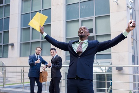 Portrait of multi ethnic business team. Three happy smiling men standing against the backdrop of the...