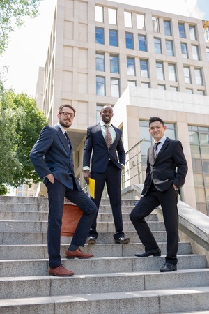 Portrait of multi ethnic business team.Three smiling men standing against the background of city....
