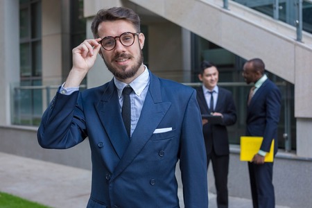 Portrait of multi ethnic business team.Three men standing against the background of city. The foreground of a European man. Other men is Chinese and African-American. The concept of success of the transactionの写真素材