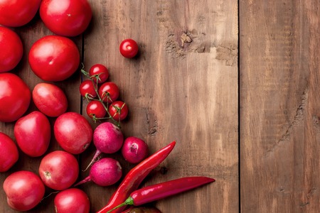 The set of red vegetables and spices on wooden table, copy space image - tomatoes, radish, pepperの写真素材