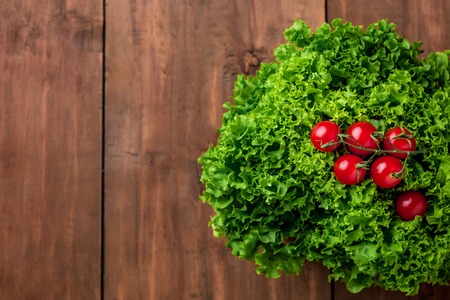 lettuce salad  and red cherry tomatoes on a gray wood background. copy space imageの写真素材