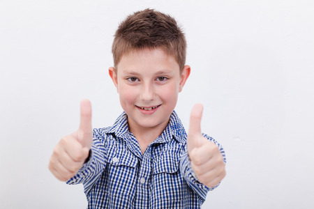 Portrait of happy boy showing thumbs up gesture,  over white backgroundの写真素材