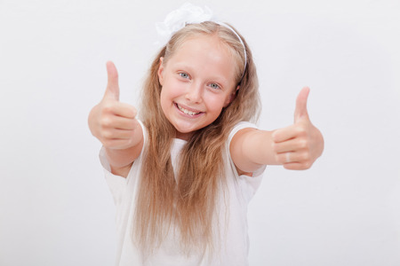 Portrait of a beautiful smiling girl showing thumbs up on white backgroundの写真素材