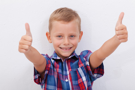 Portrait of happy boy showing thumbs up gesture,  over white backgroundの写真素材