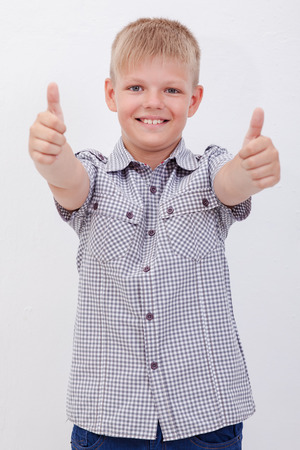 Portrait of happy boy showing thumbs up gesture,  over white backgroundの写真素材
