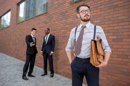 Portrait of multi ethnic business team.Three men standing against the background of city. The foreground of a European man. Other men is Chinese and African-American. The concept of success of the transactionの写真素材