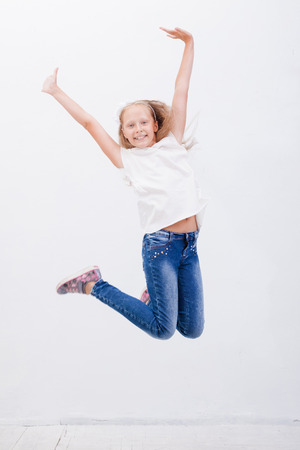 happy young girl jumping over a white backgroundの写真素材