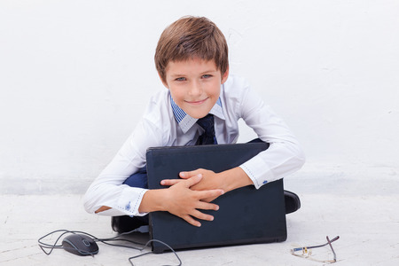 The smiling boy using his laptop computer on white background.の写真素材