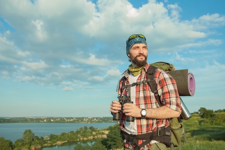 Young smilimg caucasian tourist with backpack  standing on the top of hill. The concept of an invitation to travelの写真素材
