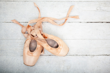The old pointe shoes on white wooden background, copyspace imageの写真素材
