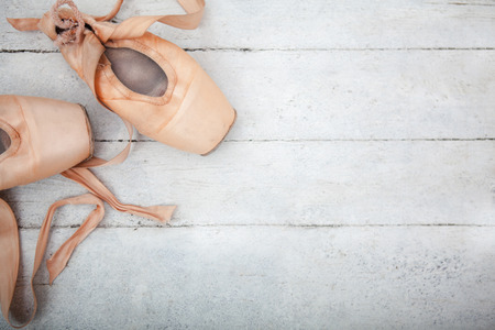 The old pointe shoes on white wooden background, copyspace imageの写真素材