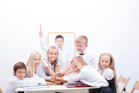 The front view of group of teen pupils. They holding their hands together on white backgroundの写真素材