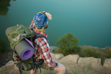 Young caucasian tourist with backpack on the top of hill. back viewの写真素材