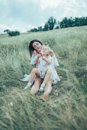 The young mother and daughter with candies on green grass backgroundの写真素材