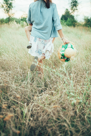 The back view of young mother and daughter on green grass background.の写真素材