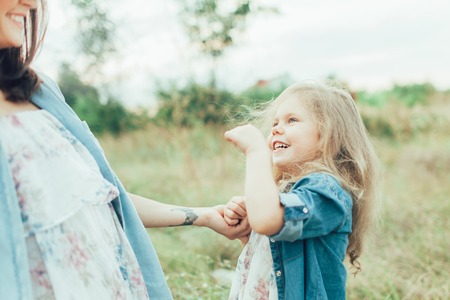 The side view of young mother and daughter with hats on green grass backgroundの写真素材