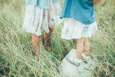 The side view of young mother and daughter on green grass background. feet close-upの写真素材