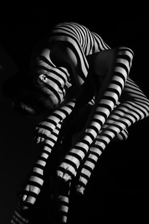 The nude woman and her reflection with black and white zebra stripes.  Black-and-white photo created with the projectorの写真素材
