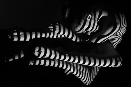 The nude woman and her reflection with black and white zebra stripes.  Black-and-white photo created with the projectorの写真素材