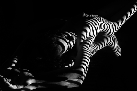 The nude woman and her reflection with black and white zebra stripes.  Black-and-white photo created with the projectorの写真素材