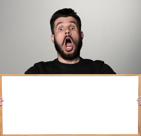 The surprised man and empty white blank or copyspace over gray backgroundの写真素材