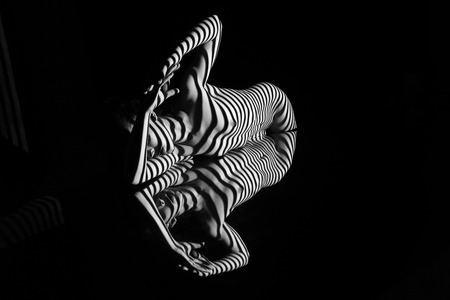 The nude woman and her reflection with black and white zebra stripes.  Black-and-white photo created with the projectorの写真素材