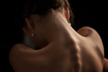A beautiful woman, back view on dark backgroundの写真素材