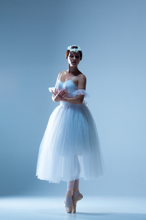 Portrait of the classical ballerina  in white dress on blue backgroundの写真素材