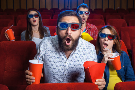 A variety of human emotions of friends holding a cola and popcorn in the cinema.の写真素材