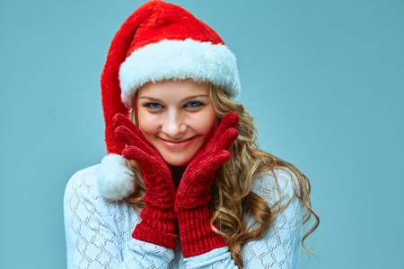 The smiling happy girl dressed in santa hat. Holiday concept with blue background.の写真素材