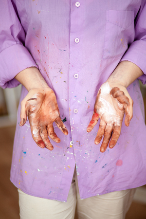 The artist girl with painted hands against the background of a lilac shirtの写真素材
