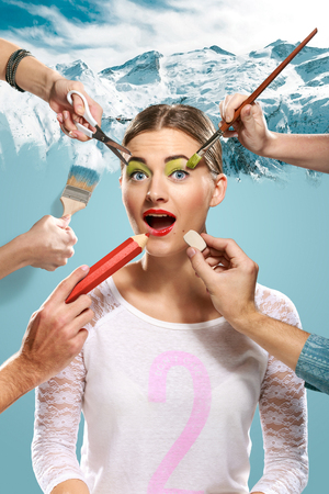 The hands of visagists doing make-up young woman  with scissors, brush, eraser and  pencil on blue backgroundの写真素材