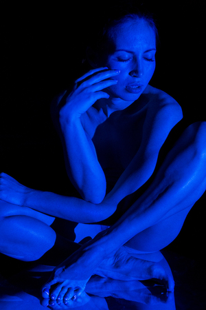The body of nude woman sitting  in the blue beam projectorの写真素材