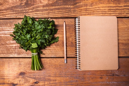 Blank notebook and pencil with a bunch of herbs on wooden boardの写真素材