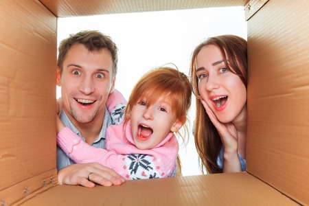 The smiling family in a cardboard box ready for moving houseの写真素材