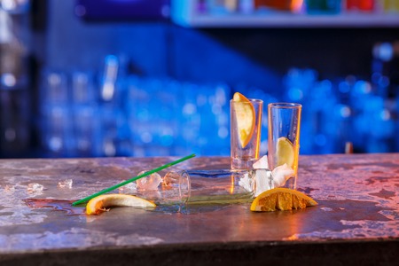 The spilled cocktails with ice cubes on blue color in the bar. concept of the end of the party