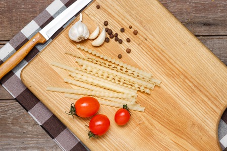 Healthy eating, noodle from the hard sorts of wheat, tomatoes, garlic on wooden tableの写真素材